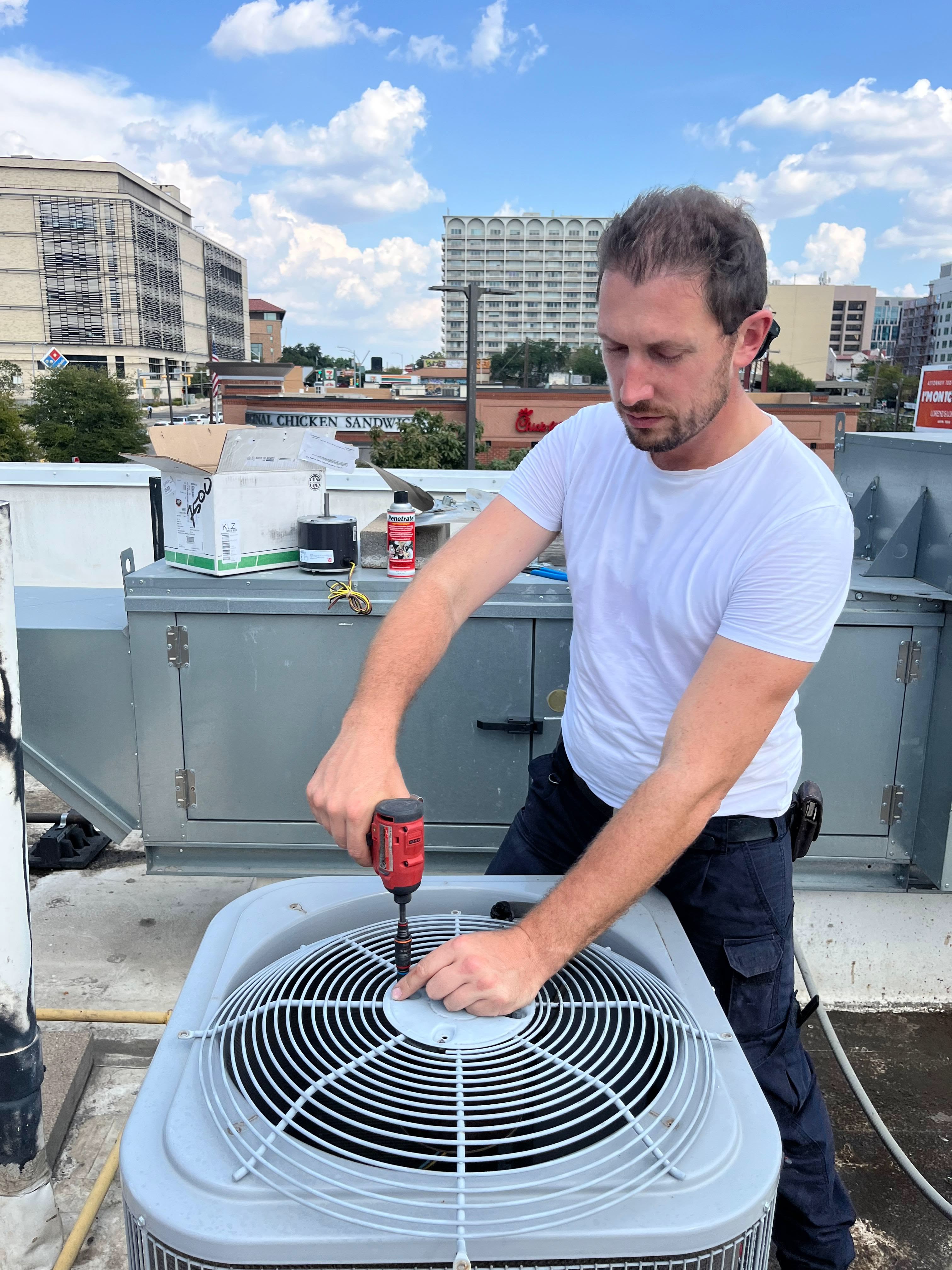 HVAC technician winterizing an outdoor AC condenser unit, shielding it before snow and cold weather arrives